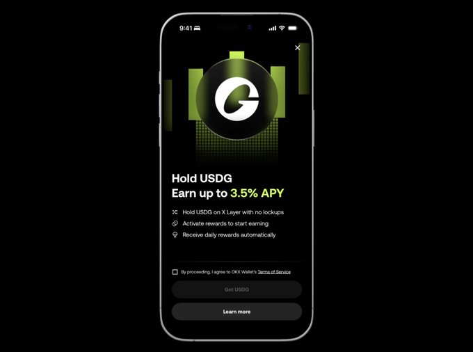 A mobile phone screen displays a promotional prompt for holding $USDG with a green "G" logo, advertising "Earn up to 3.5% APY" with bullet points highlighting no lock-ups, automatic daily rewards, and activation requirements through OKX Wallet's Terms of Service. The image directly illustrates the post's offer of up to 3.5% APY on USDG via OKX Wallet, featuring a "Get USDG" button and a "Learn more" option.