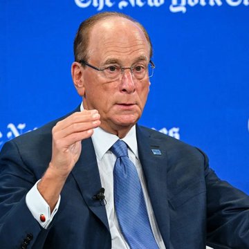 The image shows a man wearing a suit with glasses and sitting down. He appears to be looking off-camera or at the audience while giving a speech. The text on the screen reads, "BREAKING The BlackRock ETF has sold $1,750,000,000 worth of Bitcoin this month already." This indicates that the man might be discussing the recent rise in Bitcoin prices and its potential impact on various asset classes.