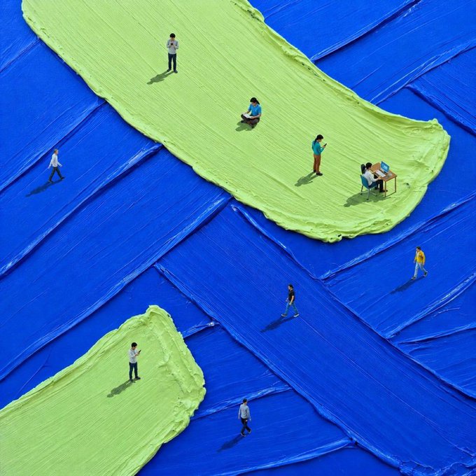 An artistic overhead image of people standing on green paint strokes applied over a blue tarp, creating a creative landscape effect.