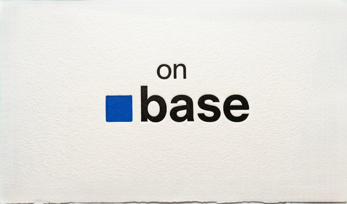 A minimalist logo on textured white paper displaying 'on base' in black lowercase text next to a solid blue square.
