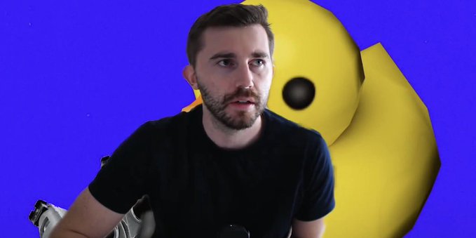 A man in a black shirt looking off-camera against a purple background featuring a large yellow smiley face.