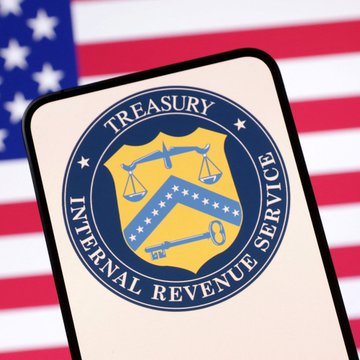 The Internal Revenue Service (IRS) Treasury seal is displayed on a phone screen with the American flag in the background.