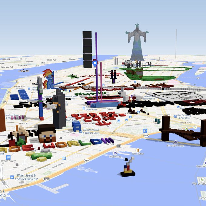 A Minecraft-style 3D map of Lower Manhattan features various blocky characters and structures, including a tall statue and a large 'F' logo, overlaid on a real-world street map.