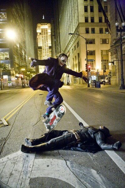 A skateboarder in a purple suit jumps over a person in a black costume lying on a city street at night, captioned "How it feels to make a positive trade on Pumpfun." The image humorously depicts the skater soaring triumphantly while the downed figure represents losses or unsuccessful trades.