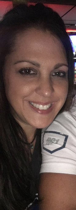 A smiling woman with dark hair takes a selfie, wearing a white t-shirt featuring an "RX-1" patch on the shoulder, playfully embodying her "Wegenette" alter ego as described in the caption.