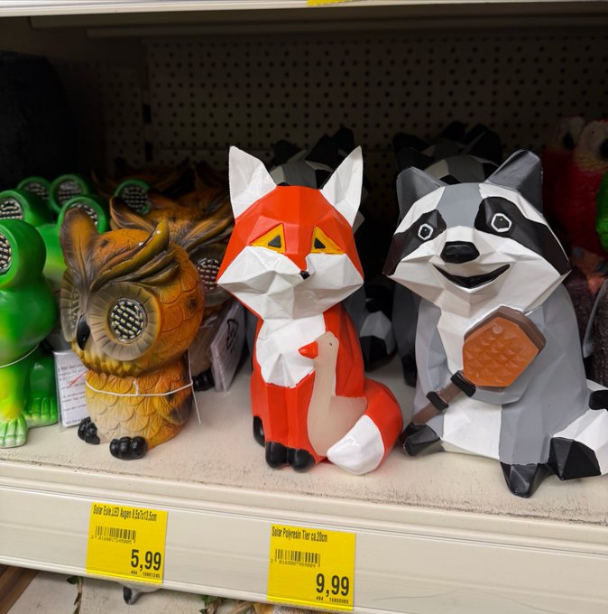 Store shelf featuring 3D paper animal figurines with price tags reading "Solar Gato LED Accent $5.99" and "Solar Polystone Fox ou Raccoon $9.99," showing a red fox and a gray raccoon posed together resembling the MetaMask fox logo.