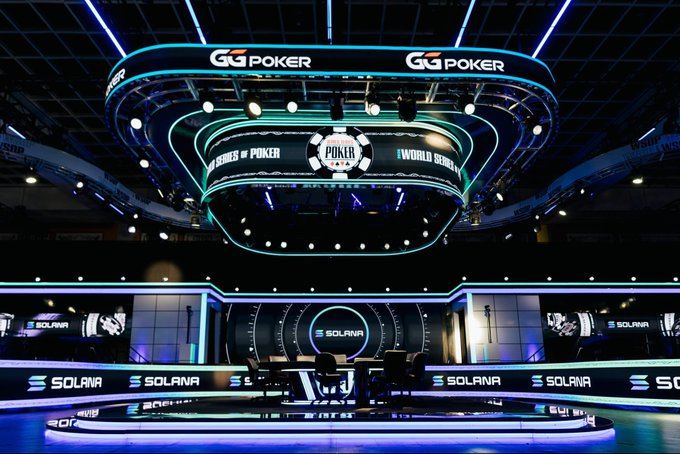 The image shows an indoor event space, possibly a casino or a poker tournament venue, featuring a large stage with blue lighting and a circular logo for G3 Poker. The stage appears to be set up for a poker game, as there are chairs placed around it. A sign on the stage reads "solana being a presenting sponsor of the world series of poker is perfect players can enter tournaments with sol winners can receive instant $ in stablecoins a very aligned partnership and showing how to seamlessly weave in crypto without friction". The image also includes text that says "Solana" and "Solana", which may be related to the event or sponsorship.