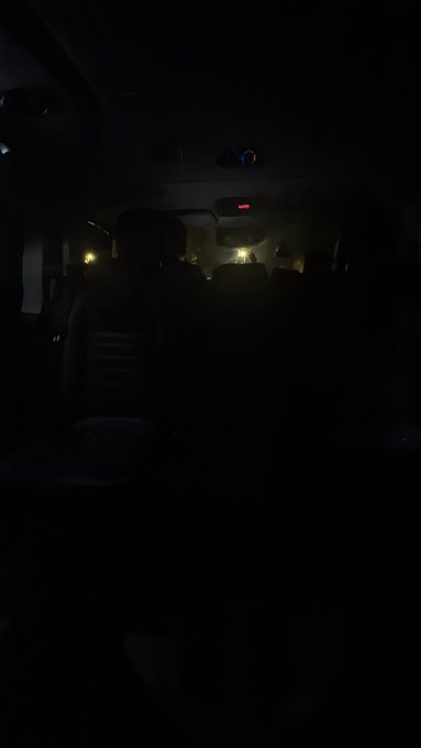 The image shows the dark interior of a car at night, with faint city lights visible through the windshield. It serves as humorous "evidence" for the caption, which jokes that if the annoyed taxi driver kidnaps the shiller, this photo should be used to find them.