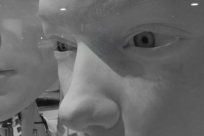 A dramatic black-and-white close-up of a person's eye and nose, with reflections visible on the face.