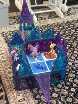 The image features a toy castle with blue and purple pieces, including a roof and walls, situated on a rug or carpeted floor. There are also small figures of animals, such as a giraffe and an elephant, placed around the castle. The text in the image reads "I think we may have found the @veefriends Honey Empire! What do you think @garyvee?". This suggests that someone has been playing with the toy castle and its animal figures, possibly creating a story or game involving these elements.