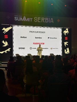 A conference stage at 'SUMMIT SERBIA' featuring a large screen displaying sponsor logos including Kulture, Kamino, Streamflow, SPEND, and others, with a speaker presenting to an audience.