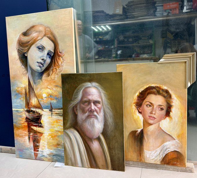 Three painted portraits displayed on a sidewalk: a woman with a boat at sunset, an older bearded man, and a young woman with auburn hair.