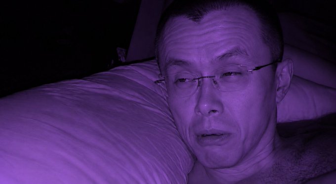 A bald man wearing glasses rests his head against a pillow in a dimly lit setting bathed in purple lighting. The mysterious purple hue and the caption "Soon..." suggest a contemplative or anticipatory moment, perhaps teasing an upcoming announcement or event.