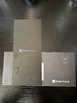 Two cardboard packages labeled "Slash Card" sit on a dark wooden surface, one taller box positioned over a wider envelope-style sleeve, with the post's mention of "JPYC & JPYSC" suggesting these are likely related to the Japanese yen stablecoin cards awaiting Solana integration support.