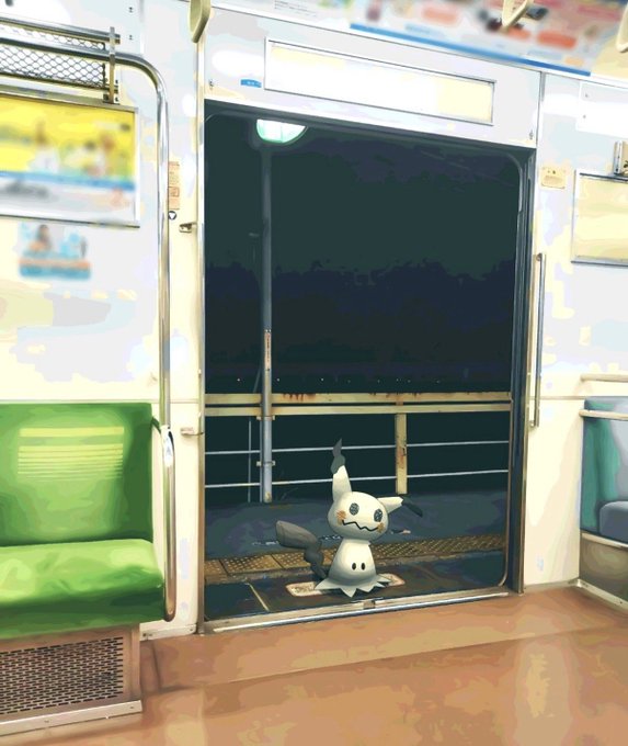 An illustrated scene inside a Japanese train car where a Mimikyu Pokémon stands at the open doorway between green seats.
