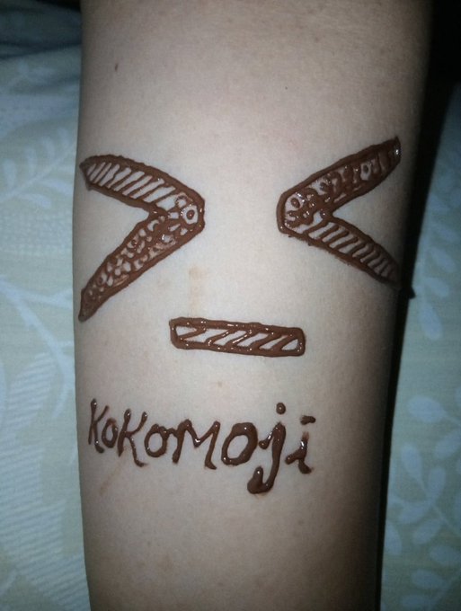 A henna tattoo on someone's arm spells out "Kokomoji" beneath a stylized face design, playfully rebranding the popular "Kokomo" meme NFT as the face of the recent NFT resurgence.