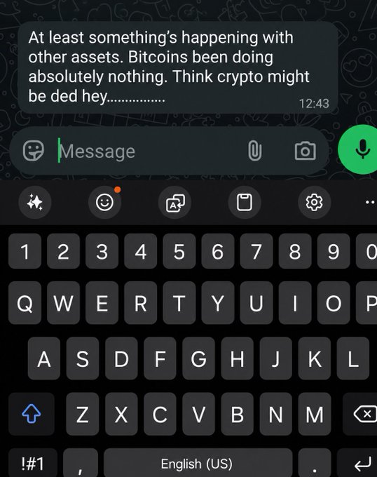 A screenshot of a WhatsApp message reading "At least something's happening with other assets. Bitcoins been doing absolutely nothing. Think crypto might be ded hey............" sent at 12:43, shown above an open keyboard. The image illustrates the bearish sentiment referenced in the post, with the friend joking that crypto is "dead" while other assets see activity.