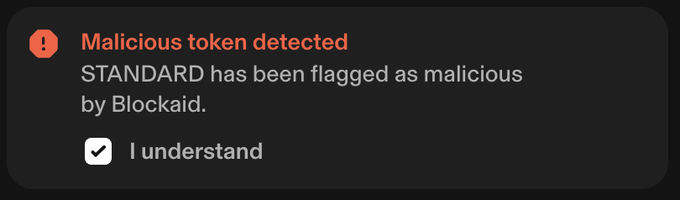 A dark warning banner displays a red exclamation mark with the text 'Malicious token detected: STANDARD has been flagged as malicious by Blockaid,' along with an 'I understand' checkbox.