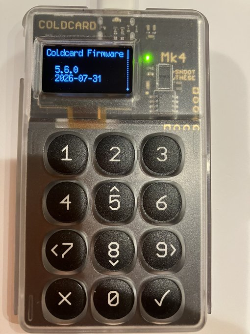 A Coinkite COLDCARD Mk4 hardware wallet displays on its screen "Coldcard Firmware 5.6.0, 2026-07-31," indicating that the device has been successfully updated with the latest firmware following the completed fund transfer.