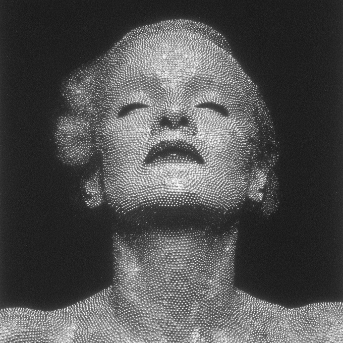 A high-contrast black and white artistic image showing a human face composed of countless tiny dots, with the head tilted back and eyes closed.