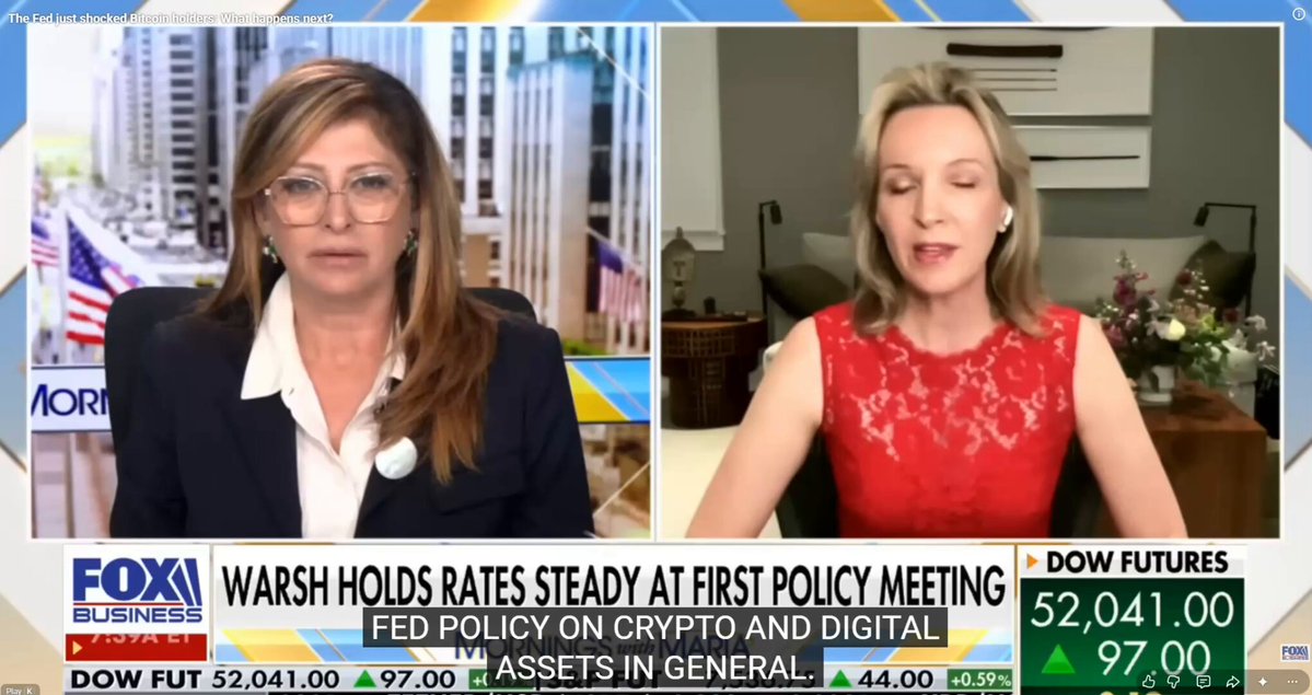 The image shows two women sitting at a desk with a TV screen displaying an interview between two experts discussing Bitcoin. One woman wears glasses and appears to be wearing a suit, while the other woman has blonde hair and is dressed more casually. The TV screen displays text that reads "SOLANA INSTITUTE PRESIDENT KRISTIN SMITH ON HOW TO THINK ABOUT BITCOIN: 
For Bitcoin specifically, it behaves a lot like gold." Not a tech stock. Not a risk asset. Not a currency. Gold. The same asset that has preserved wealth through every war, every recession, every". Focus on what is in the image and how it relates to the post.