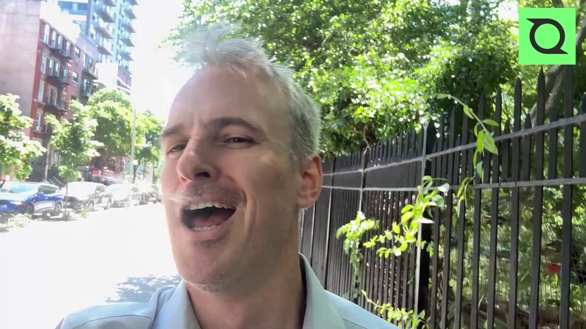 The image shows a man with a mustache wearing a white shirt standing next to a fence. The background features trees and buildings, suggesting an urban setting. There are also cars parked nearby. The caption of the image reads "NEW: Solana gRPC is now included on Scale and Business plans. No add-on, no upcharge." This indicates that the man might be discussing or sharing information about the new Solana platform for scale and business planning in a public space like a park.