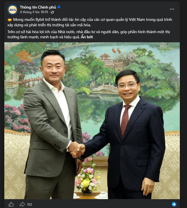 The image features two men dressed in suits shaking hands over a table with flowers. The man on the left has his hand outstretched towards the other man's hand, while both men have their arms around each other. They are standing next to a painting of a bridge and trees, which is displayed behind them. The background text indicates that this image was taken by Bybit, an online news platform.