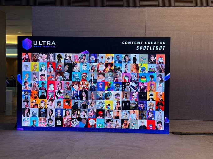 A large illuminated display board titled 'ULTRA WEAR FESTIVAL CONTENT CREATOR SPOTLIGHT' featuring a colorful collage of many illustrated avatars and cartoon characters.