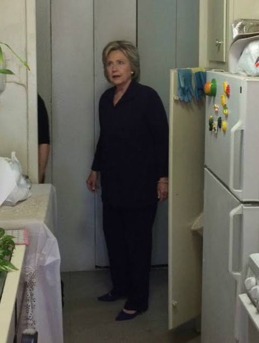In the image, a woman stands alone in a kitchen with her back turned towards the camera. She wears a black outfit that includes pants and shoes. The kitchen appears small, furnished mostly with white appliances like a refrigerator. On one of the countertops near the sink, there is some food on it. Interestingly enough, this woman seems to be discussing Bitcoin or monero in relation to an article posted online about Zcash. She might be explaining what the post is talking about, but she does not seem to be directly participating in any activity related to the topic of Bitcoin and monero at that moment.