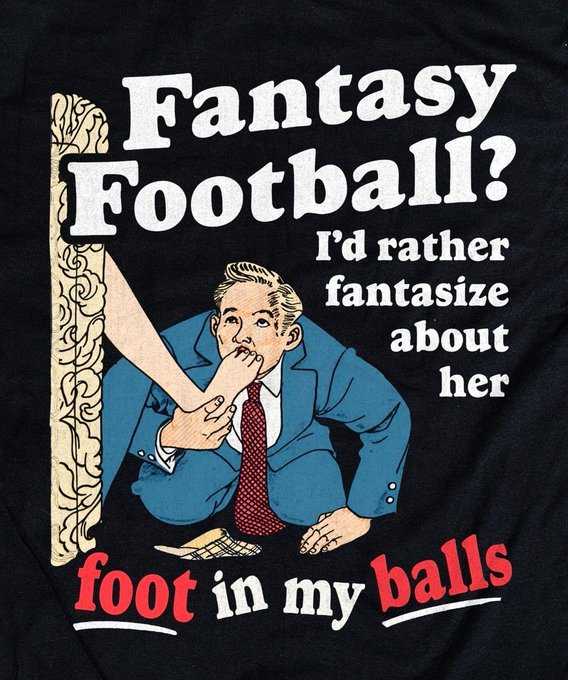 A black t-shirt with vintage-style graphic of a man being stepped on by a foot, with text reading 'Fantasy Football? I'd rather fantasize about her foot in my balls'.