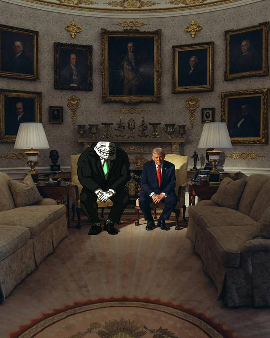 urns, paintings, and a chandelier adorn the walls of a grand room with beige carpeting, gold accents, and two men seated on sofas.