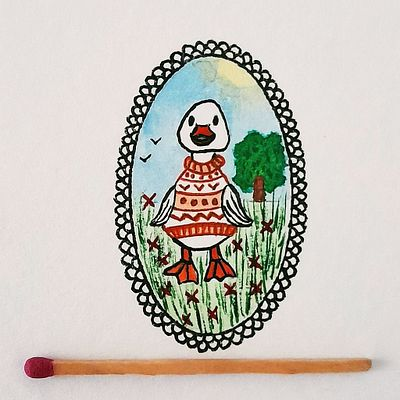 A small painting in an oval black lace-like frame depicts a duck wearing a patterned sweater, with a green tree and birds in the background; a matchstick rests below it for scale.