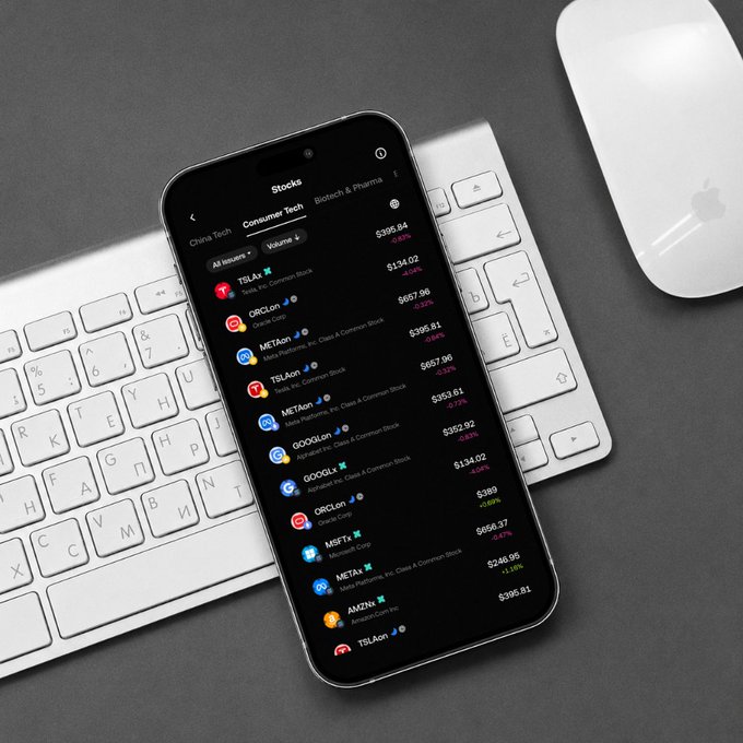 An iPhone displaying a stock trading app with a list of tech stocks including TSLA, ORCL, META, GOOGL, and MSFT showing various prices, resting on an Apple Magic Keyboard next to a white Magic Mouse.