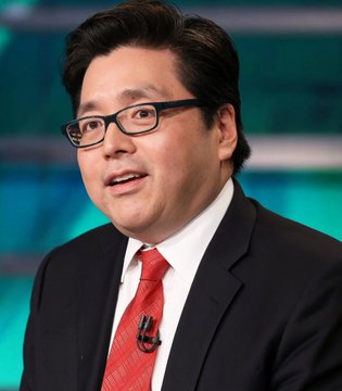 A man in a dark suit, white shirt, and red tie wears black-framed glasses while speaking on what appears to be a television set with a green and blue background. No text or identifying names are visible in the image to connect him to the accompanying post about BitMine's significant ETH holdings.