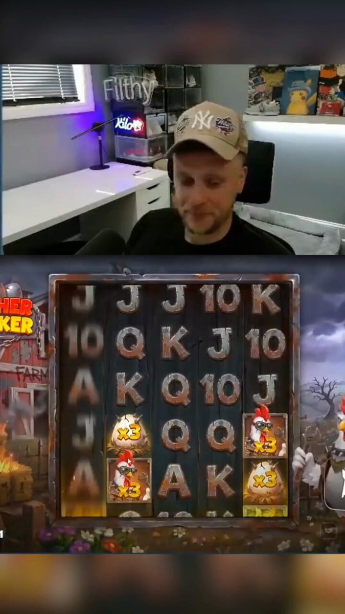 The image shows a man sitting at a slot machine, with a computer screen behind him displaying a video of the same slot machine game. The man appears to be playing the game while wearing a hat. There are several other slot machines visible in the background, suggesting that this is a popular gaming location or casino.