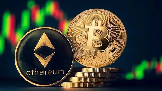 A close-up of physical Bitcoin and Ethereum (etherum) gold coins stacked together, with a blurred red and green candlestick chart visible in the dark background.