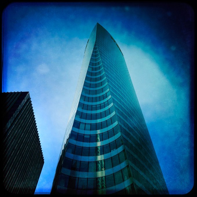 llor, a modern skyscraper with a curved facade and reflective windows, towers over the cityscape of New York, USA.