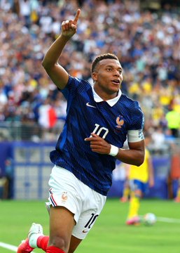 A soccer player wearing a blue #10 jersey, identifiable as Kylian Mbappé, points skyward in celebration on the pitch. The image ties to the Polymarket Golden Ball odds, visually highlighting Mbappé as the current 38% favorite to win the 2026 World Cup Golden Ball.