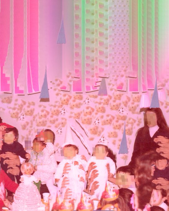 A distorted, pink-tinted vintage photograph showing a group of people at a children's party, wearing party hats, with visible visual glitches and obscured faces.