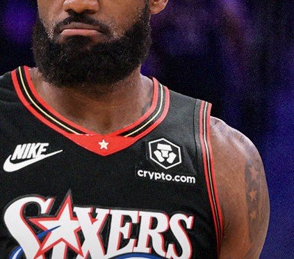A close-up of a basketball player wearing a black Sixers jersey with 'crypto.com' and Nike logos, with the team name 'Sixers' partially visible at the bottom.