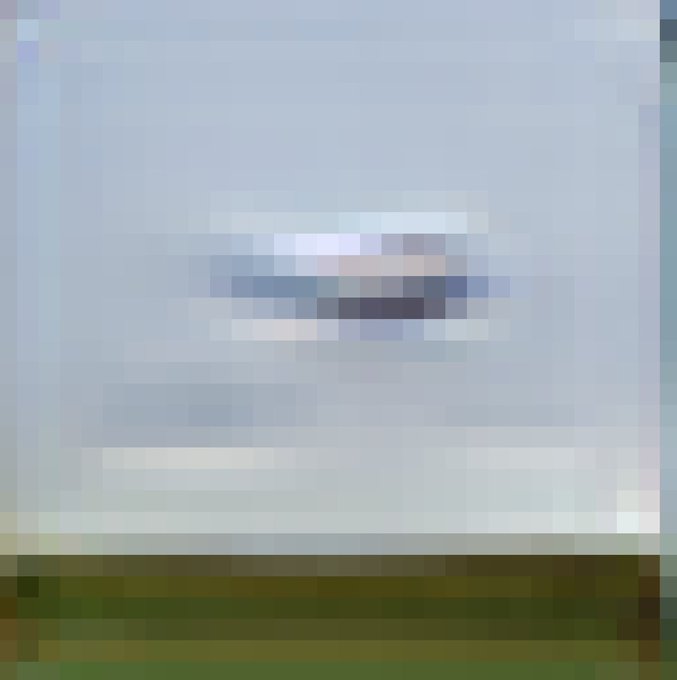 A heavily pixelated, low-resolution image showing what appears to be a small object or structure against a gray sky with a strip of green/ground at the bottom.