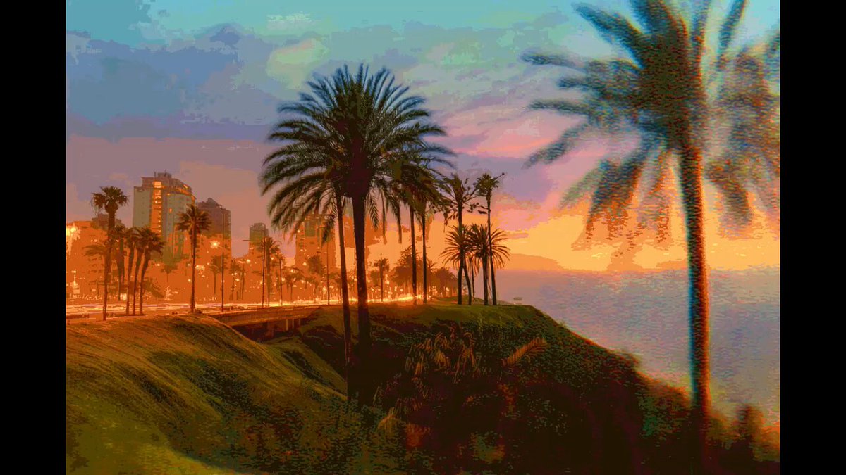 The image features a sunset over a city skyline, with palm trees lining the streets below. The sky is painted in shades of orange and blue, creating a beautiful backdrop for the urban landscape. In the foreground, there are two palm trees standing tall on a hillside overlooking the city. The photo appears to be taken from an elevated perspective, providing a unique view of both the natural beauty of the sunset and the architectural marvels of the city.