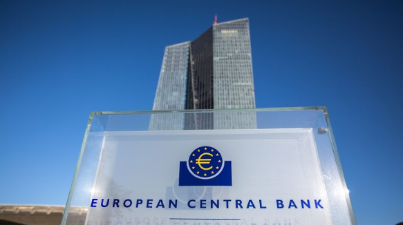 The European Central Bank headquarters building in Frankfurt, Germany, photographed from below with the official ECB logo and 'EUROPEAN CENTRAL BANK' sign in the foreground against a clear blue sky.