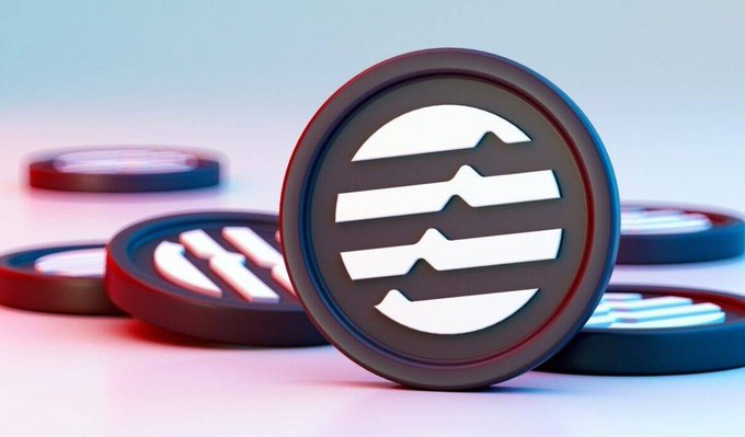 A close-up photograph of several black coins featuring a white circular logo with horizontal wave lines, resting on a white surface illuminated by pink and blue lighting.