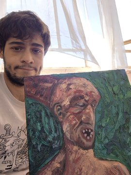 The image features a man holding an oil painting of a person's face with a green background. The painting has a skull design on the face, which adds a unique artistic touch to the piece. The man appears to be posing for the photo while showcasing his artwork.