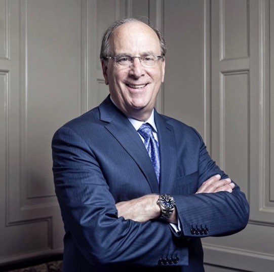 A smiling middle-aged man in a blue suit stands with his arms crossed in a paneled office; no readable names, tickers, or numbers appear in the image. The accompanying post claims that BlackRock ETFs bought $665 million worth of Bitcoin, though the image itself does not provide visual confirmation.