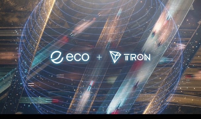 A graphic announcement showing the logos of 'eco' and 'TRON' with a plus sign, set against an aerial view of a complex highway interchange at night with digital light effects.