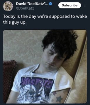 The image is a screenshot of a tweet from David "JoelKatz" (@JoelKatz) reading "Today is the day we're supposed to wake guy up," featuring a photo of a sleeping young man in a Misfits t-shirt with visible tattoos. The accompanying post references Green Day's "Wake Me Up When September Ends," equating "September" to 10/7—the date of the October 7 Hamas attacks on Israel—implying the sleeping figure symbolizes Israelis who were caught unaware during the attack.