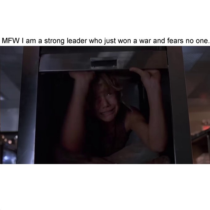A meme-style image shows a person clinging to the underside of an ATM with a panicked expression, captioned 'MFW I am a strong leader who just won a war and fears no one.'
