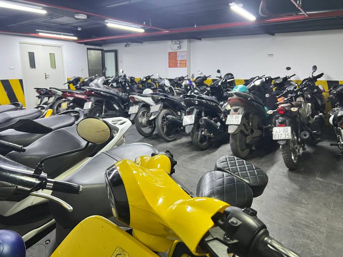 The image shows a large collection of motorcycles parked inside a garage or storage area, with some of them being yellow. The motorcycles are arranged in rows, occupying most of the space available. In addition to the motorcycles, there are also several chairs placed around the room, providing seating for people who may be interested in admiring the bikes or socializing among themselves.